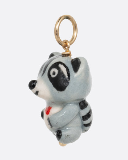 A hand painted raccoon charm with a bow tie. Shown from the side.