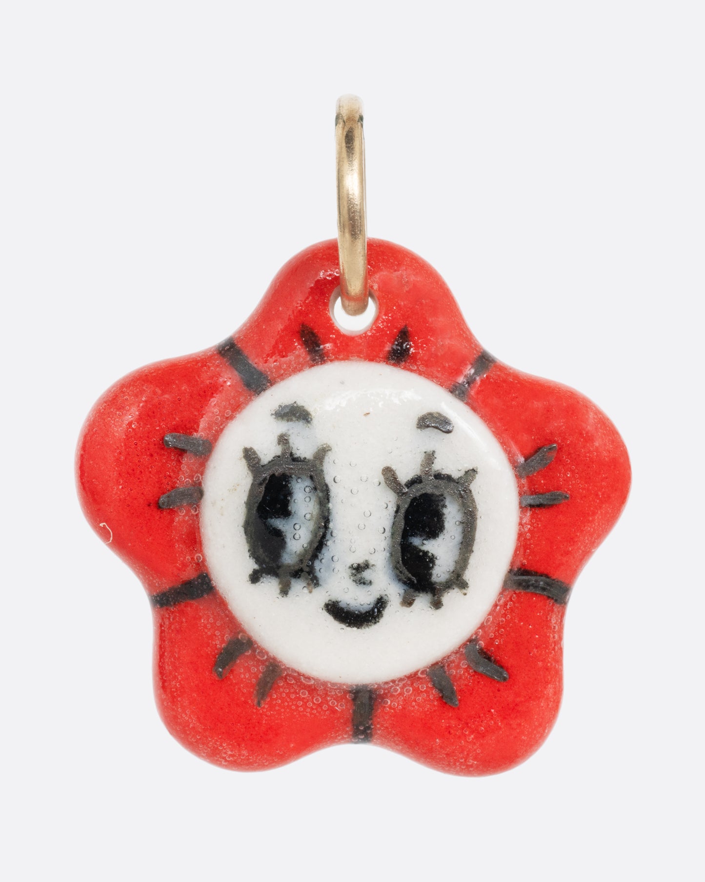 A red flower porcelain flower charm with a face at the center. Shown from the front.