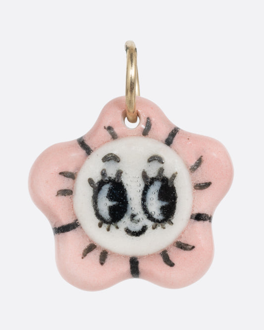 A pink flower porcelain flower charm with a face at the center. Shown from the front.
