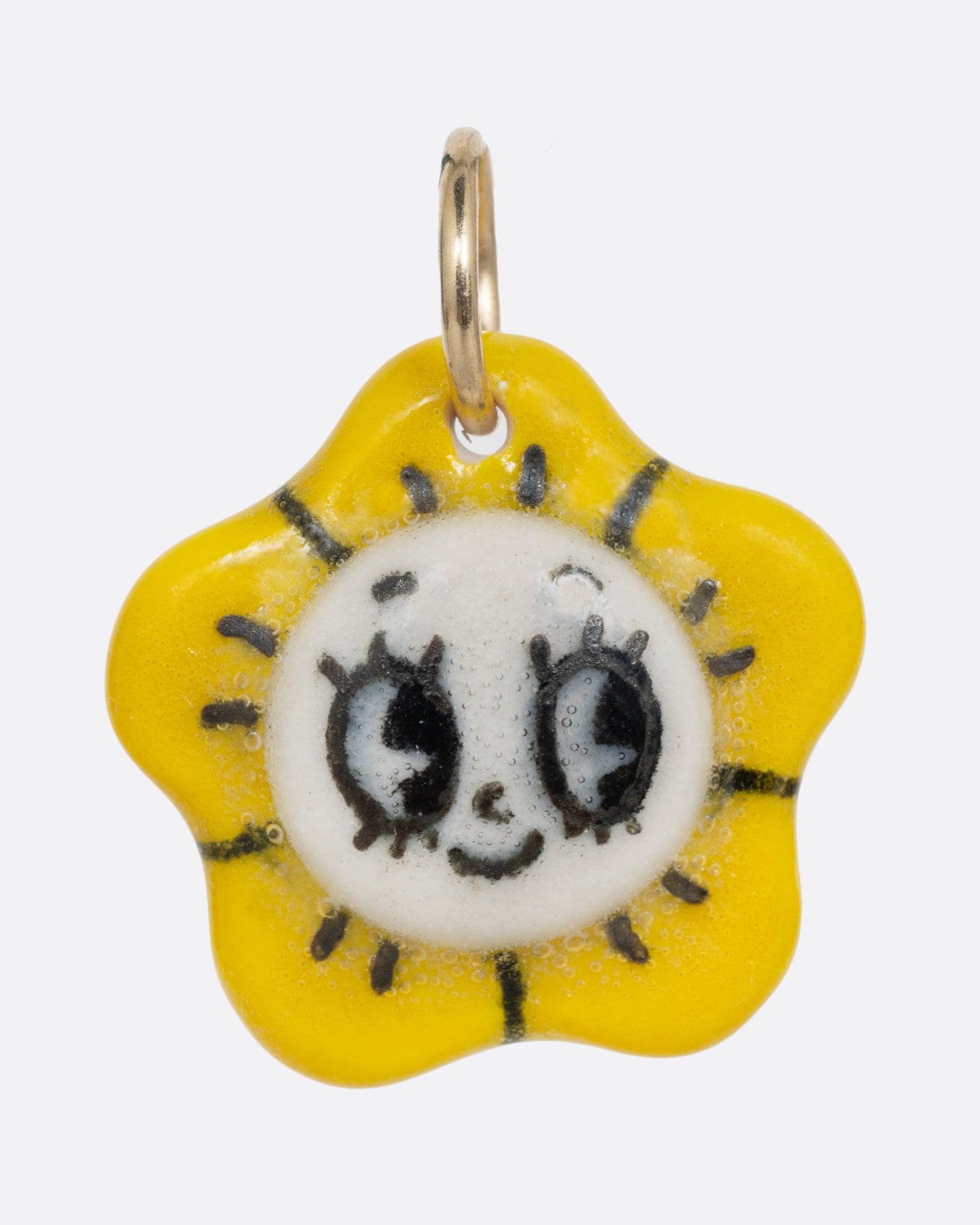 A yellow flower porcelain flower charm with a face at the center. Shown from the front.