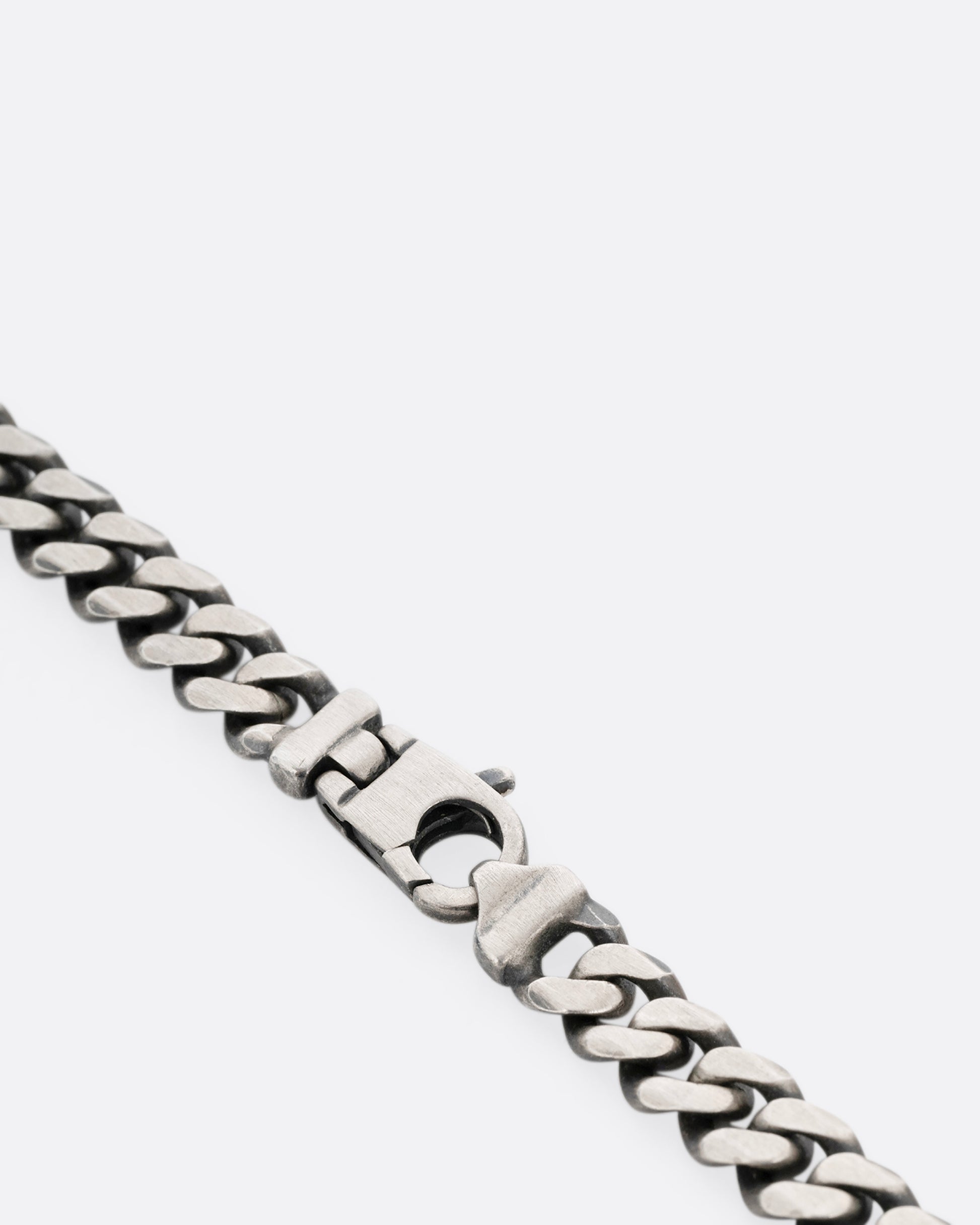 A close up of a silver curb chain necklace.