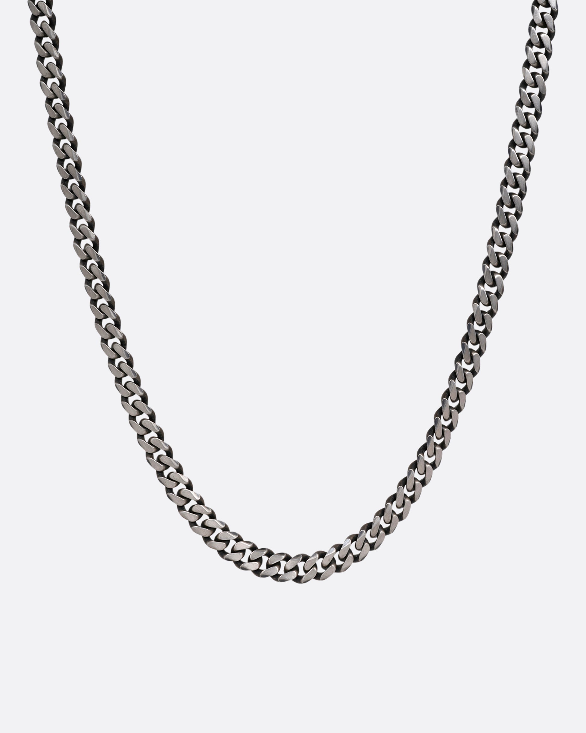 A silver curb chain necklace shown from the front.
