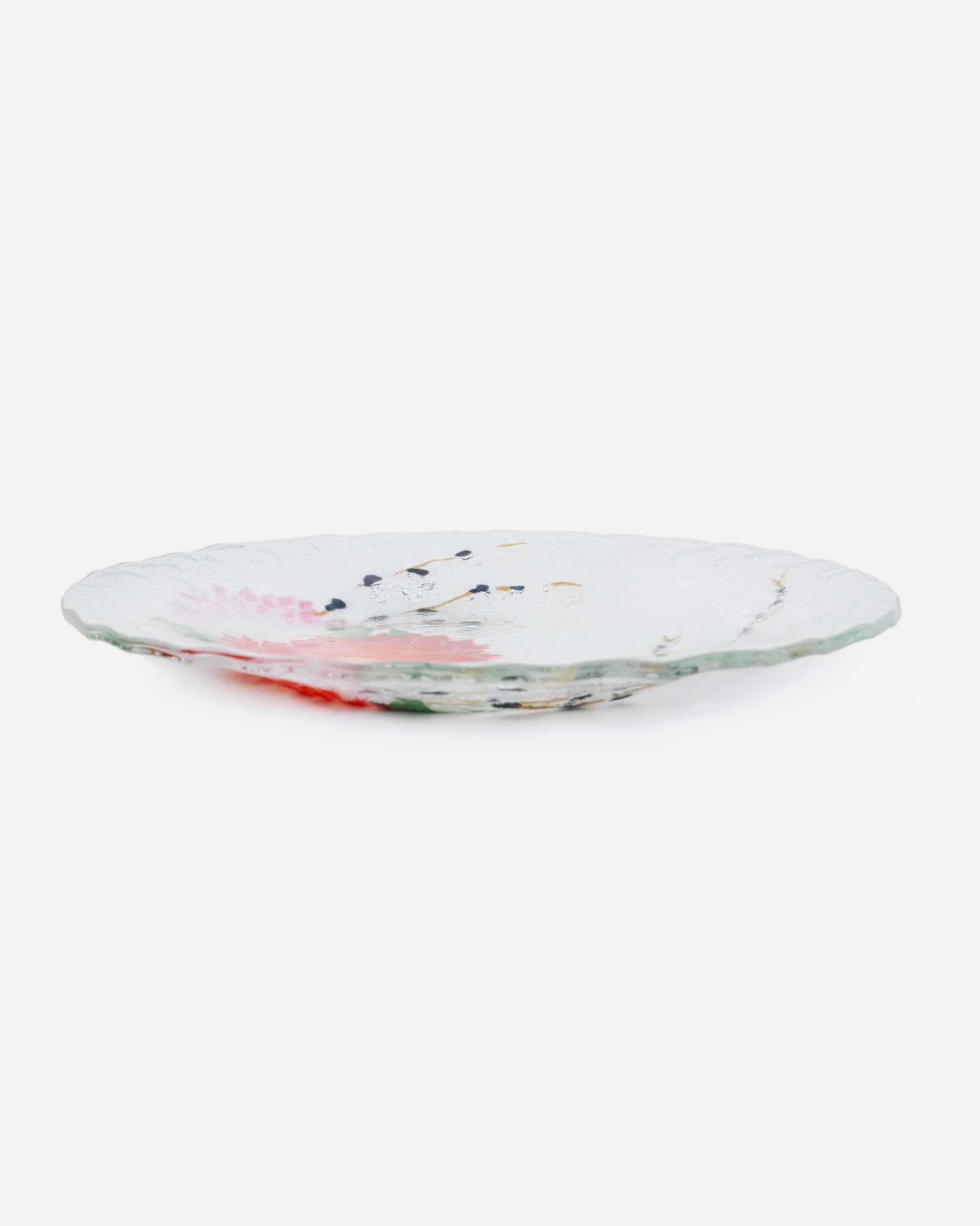 A clear fused glass plated with a chrysanthemum motif. Shown from the side.