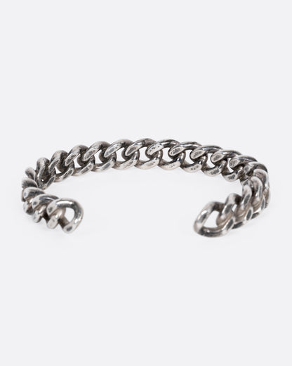 A silver curb chain cuff bracelet shown from the back.