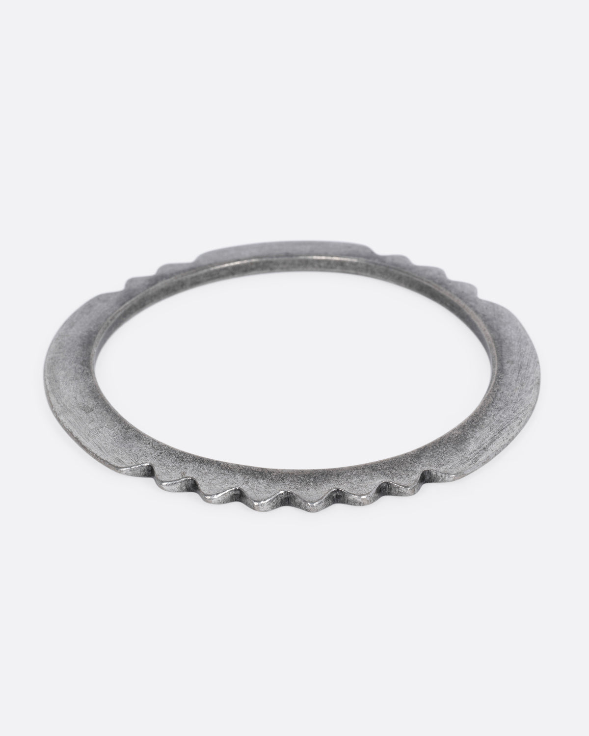 A silver bangle bracelet with a zigzagging edge, shown from the front.