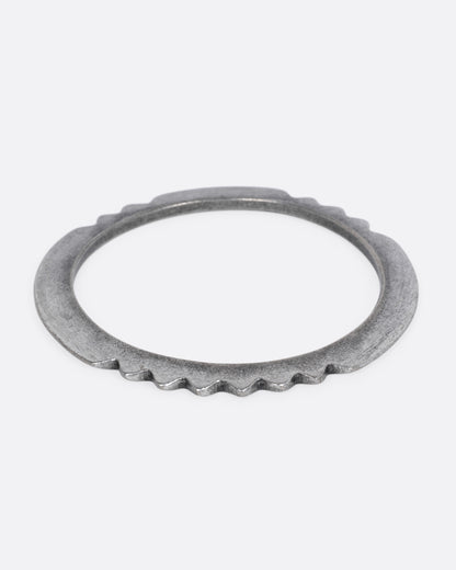A silver bangle bracelet with a zigzagging edge, shown from the front.