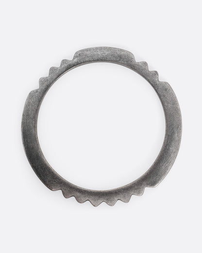 A silver bangle bracelet with a zigzagging edge, shown from the top.