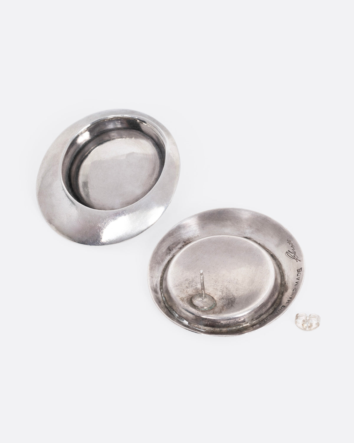 A pair of round stud earrings with recessed centers. One earring is shown from the front, the other is open from the back.
