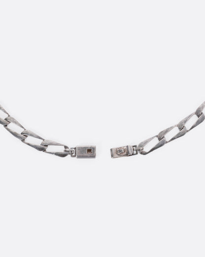 A close up of the clasp of a silver chain with elongated oval links.