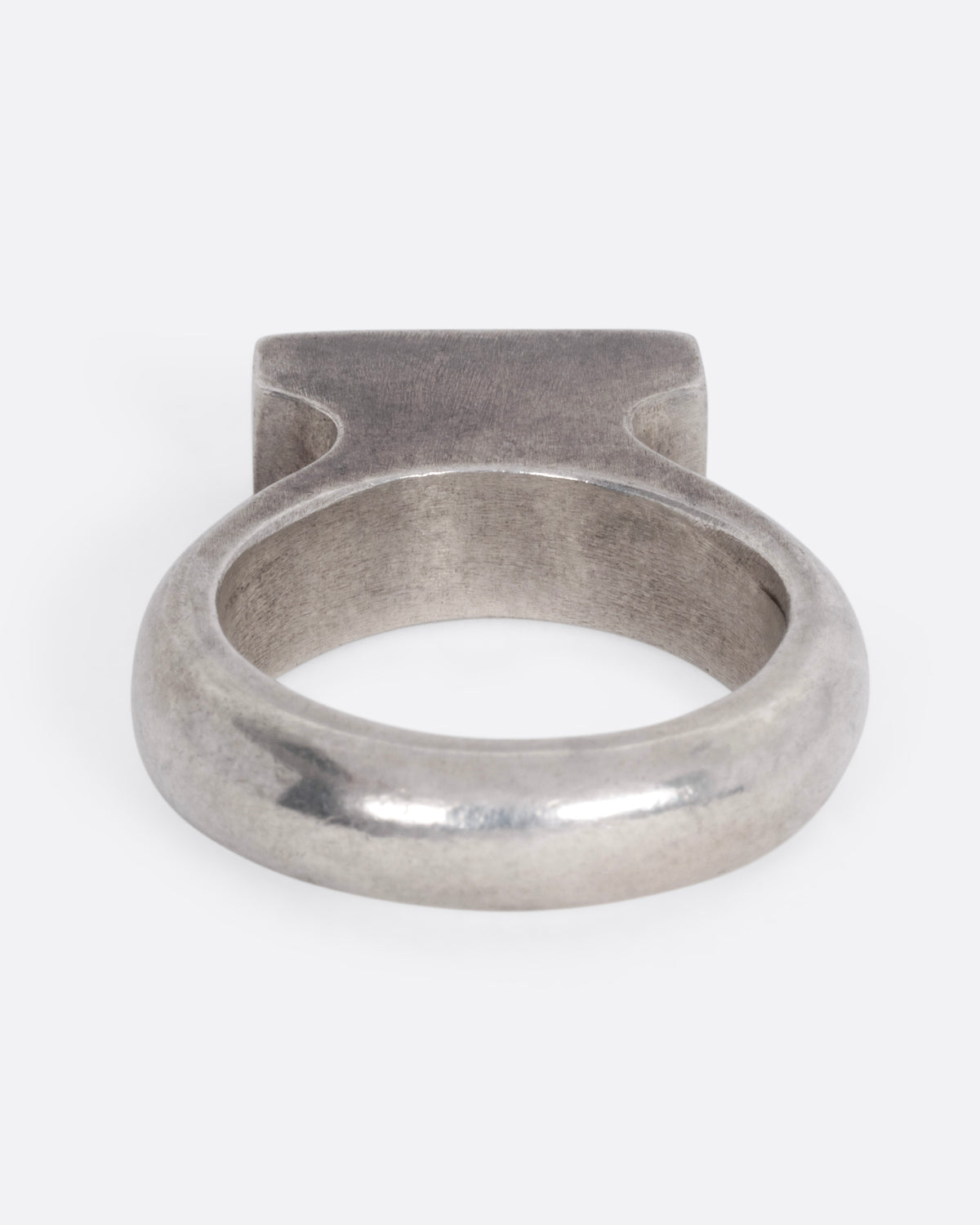A silver rectangular signet ring with a high silhouette and flat top, shown from the back.