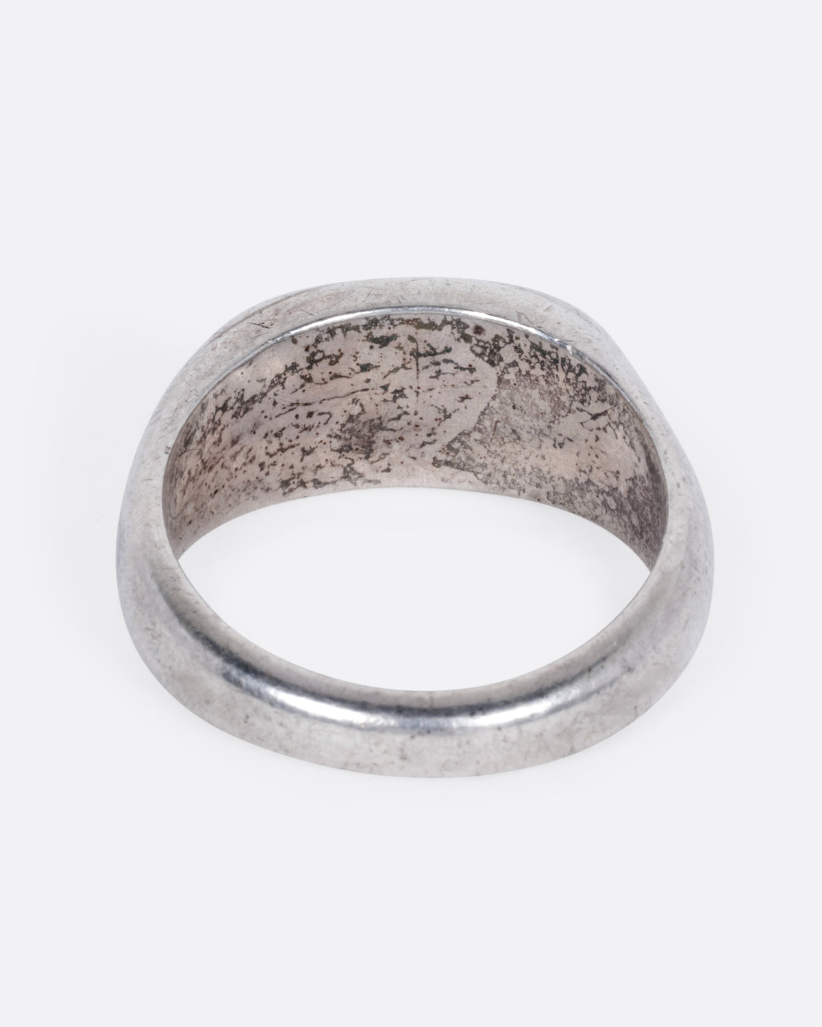 A silver signet ring with a faint engraving of 'GS' on its broad face, shown from the back.