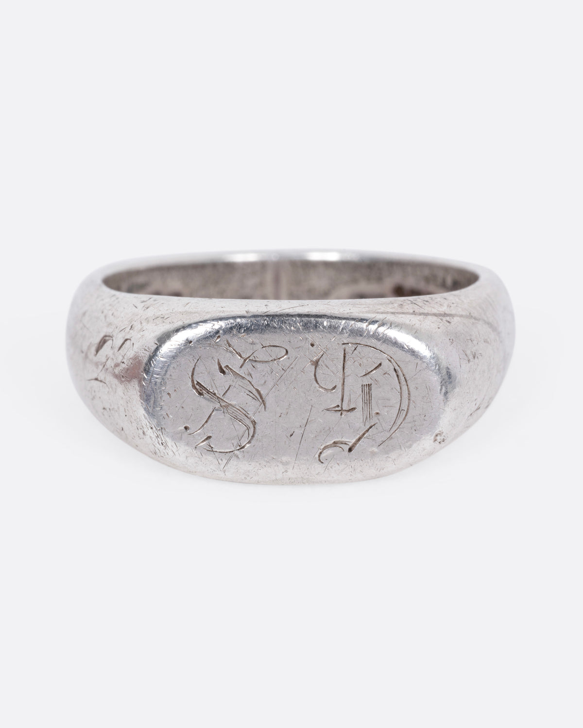 A silver signet ring with a faint engraving of 'GS' on its broad face, shown from the front.