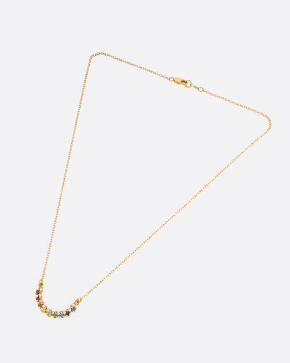 A yellow gold cable chain necklace with a crescent shaped pendant with multicolored gemstones, shown from the front.