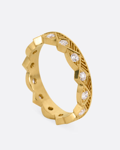 A yellow gold ring with a zigzag design and diamonds throughout, shown from the side standing up.