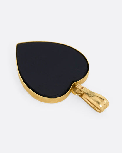 A yellow gold heart shaped pendant with opal inlay, shown from the back.