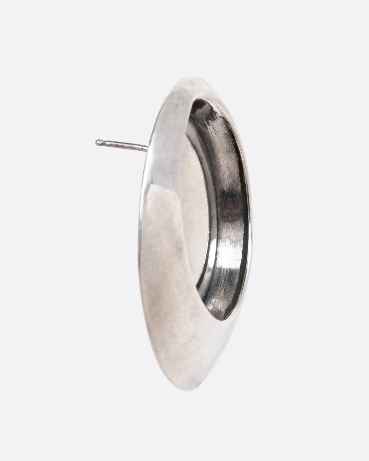 A ound stud earring with a recessed center, shown from the side.