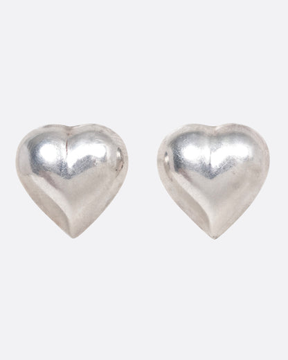 A pair of silver heart shaped stud earrings shown from the front.