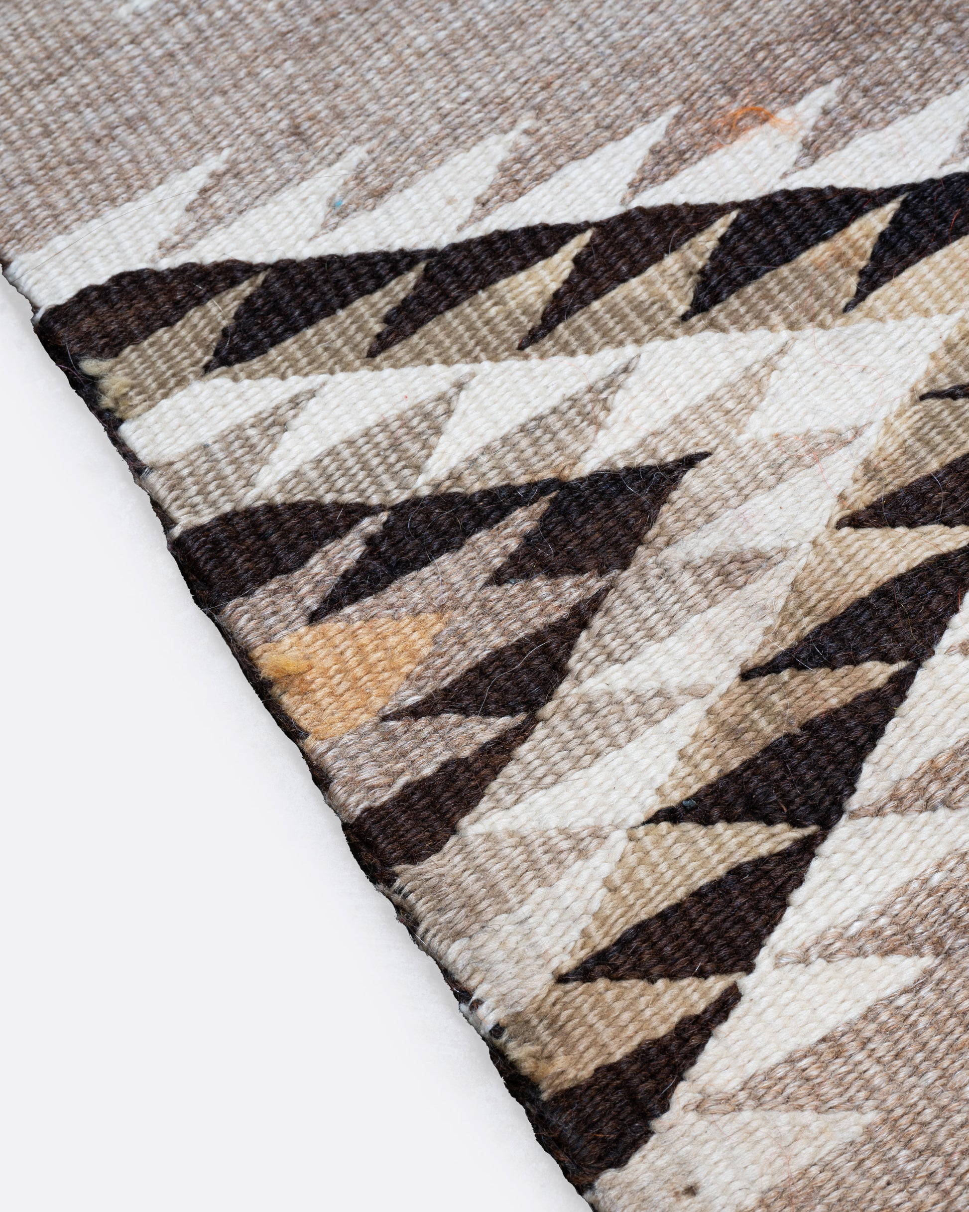 A close up of a tan, black, and white Navajo Diamond Eye Dazzler rug with a serrated diamond motif.