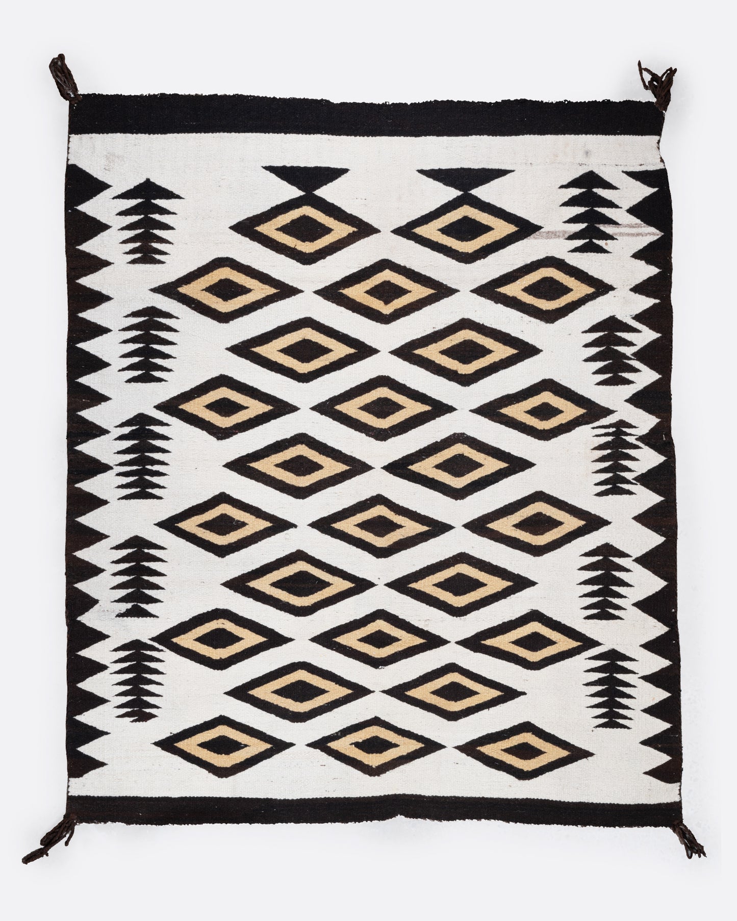 A bird's eye view of a white, black, and yellow Navajo Crystal weaving rug with a bold border and stacked diamond pattern.