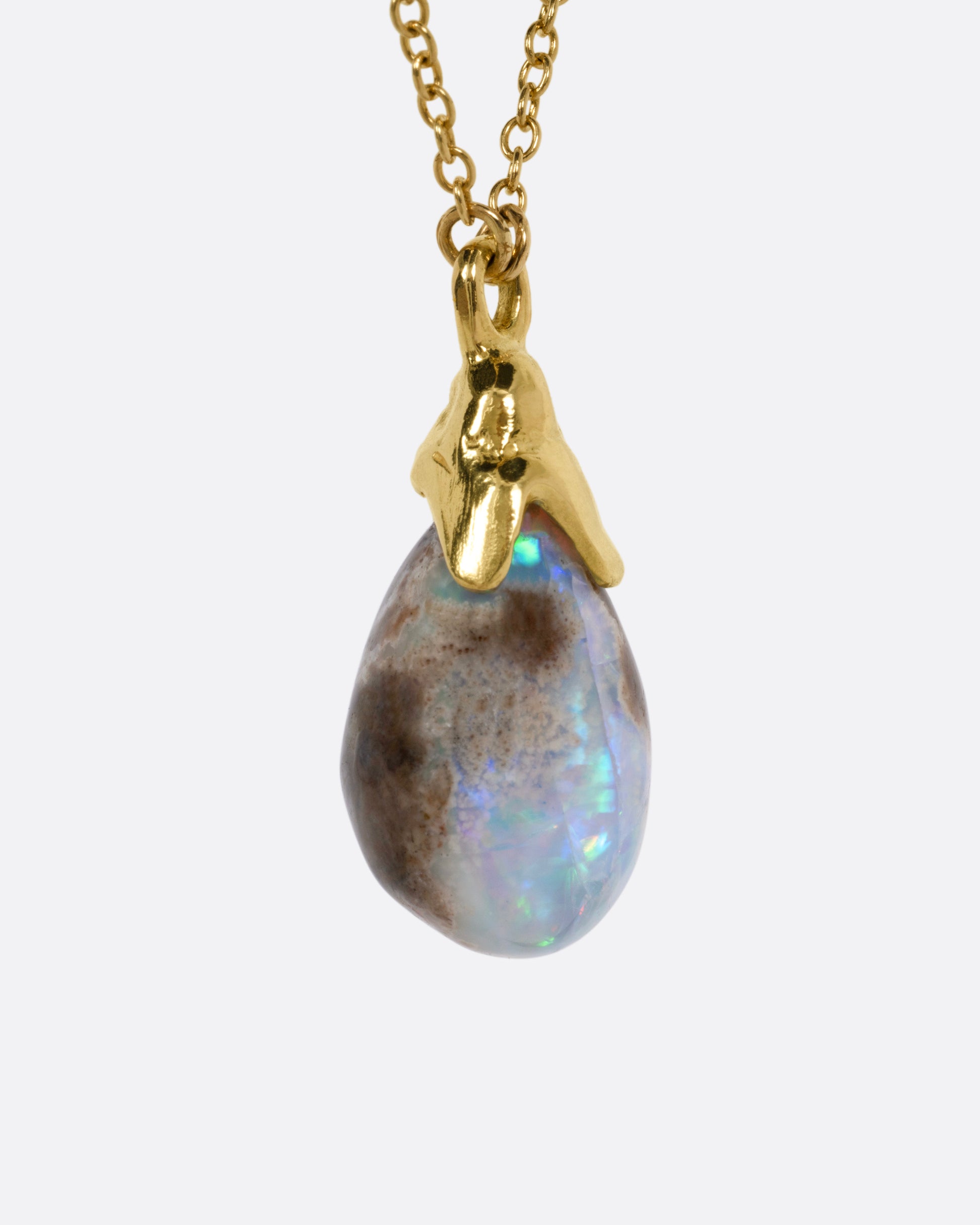 A yellow gold necklace with a teardrop shaped opal pendant, shown from the side.