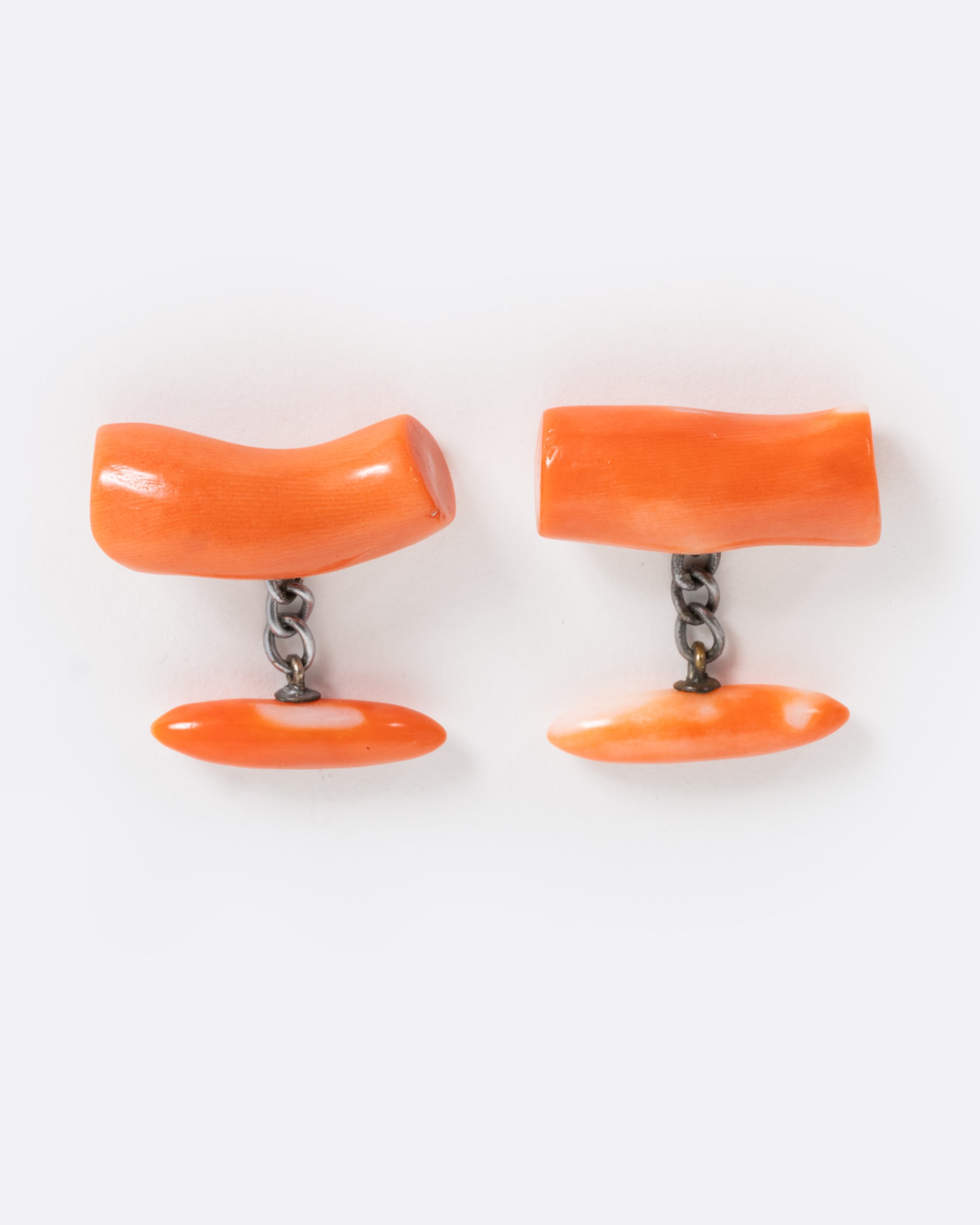 A pair of coral cuff links shown from the front.