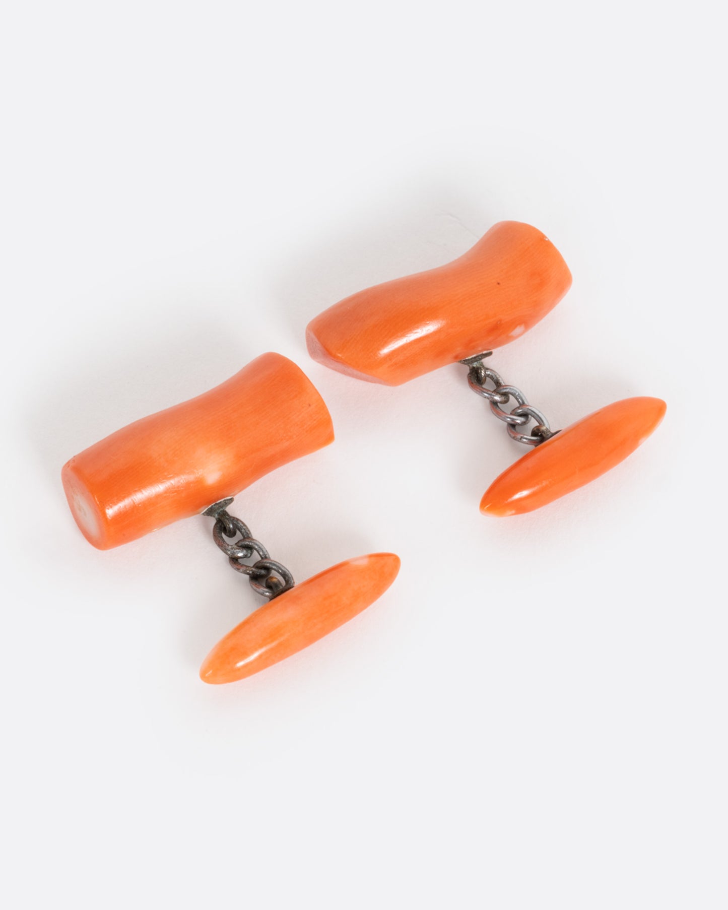 A pair of coral cuff links shown from the front.