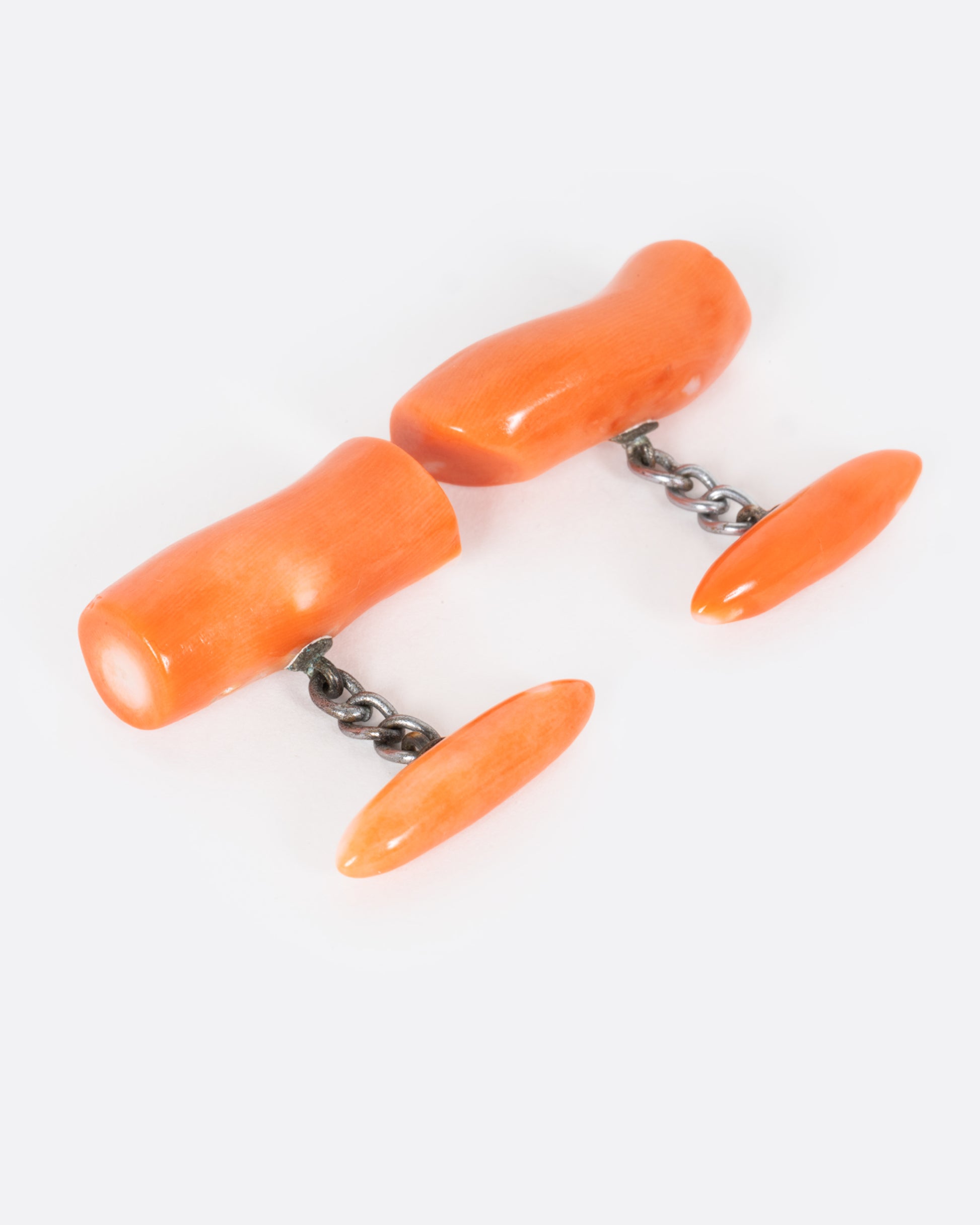 A pair of coral cuff links shown from the side.