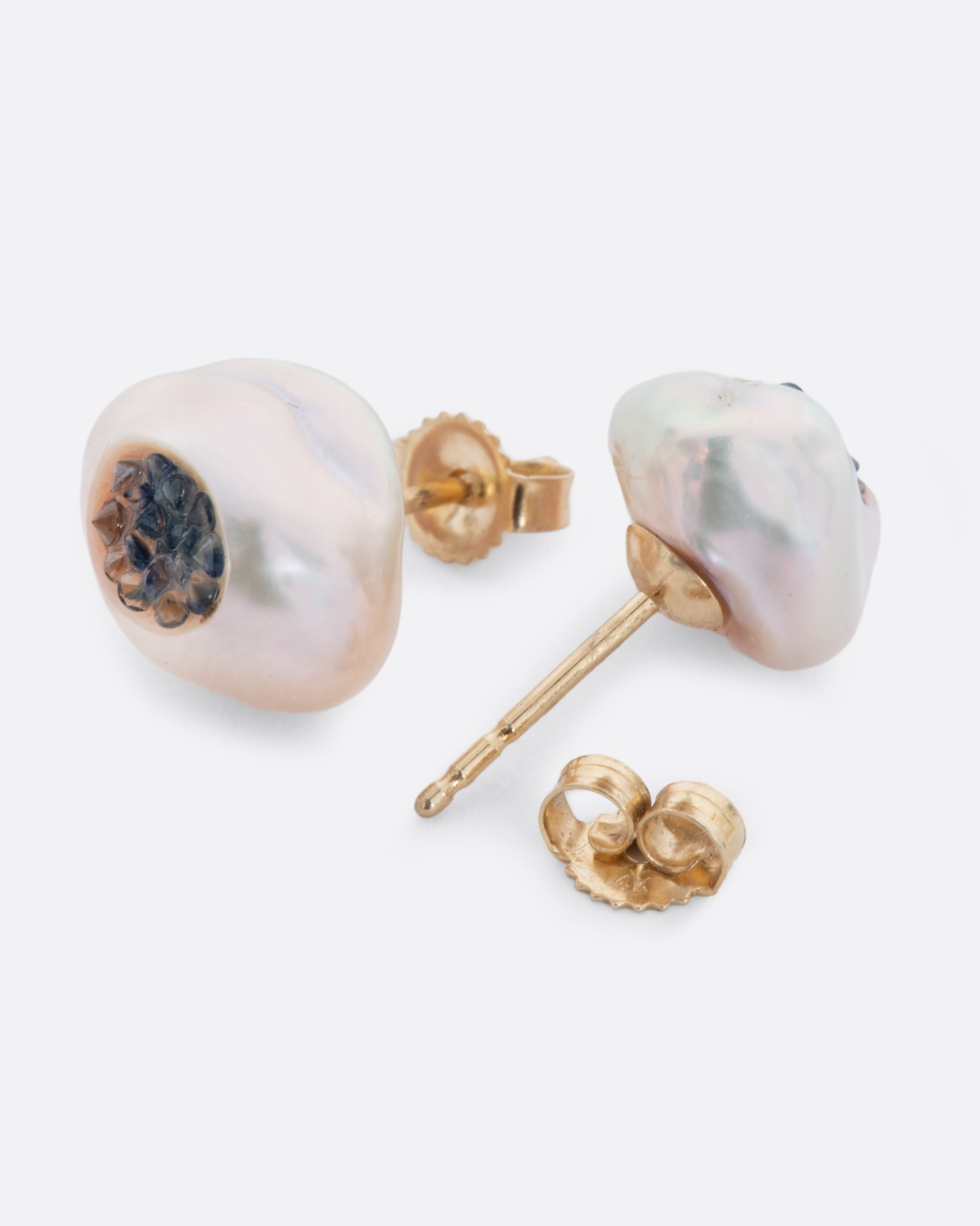 A pair of yellow gold earrings with hollowed out pearls filled with sapphires. Shown from the front and back alternating.