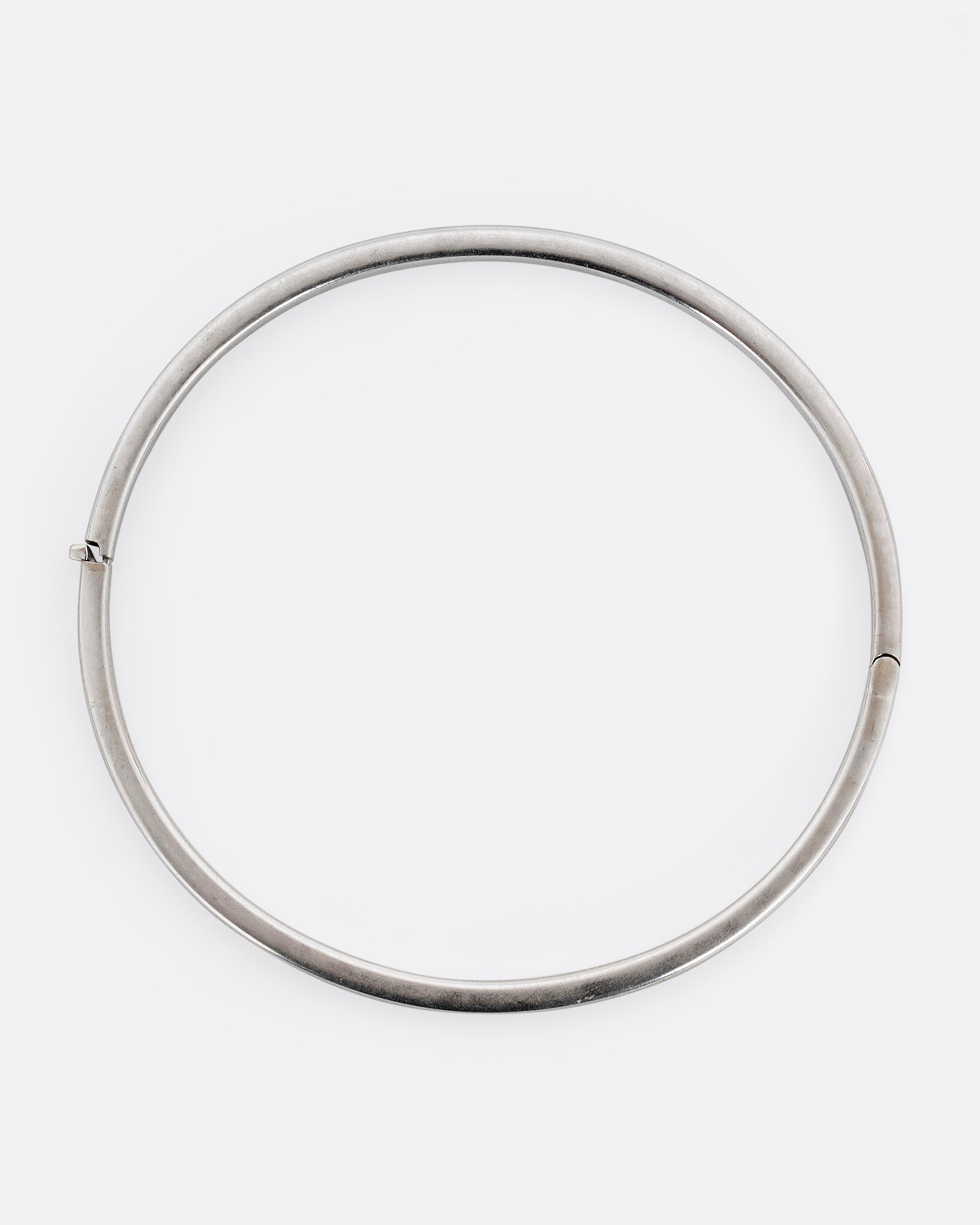 A silver hinged  bangle bracelet with squared edges. Shown from the top.