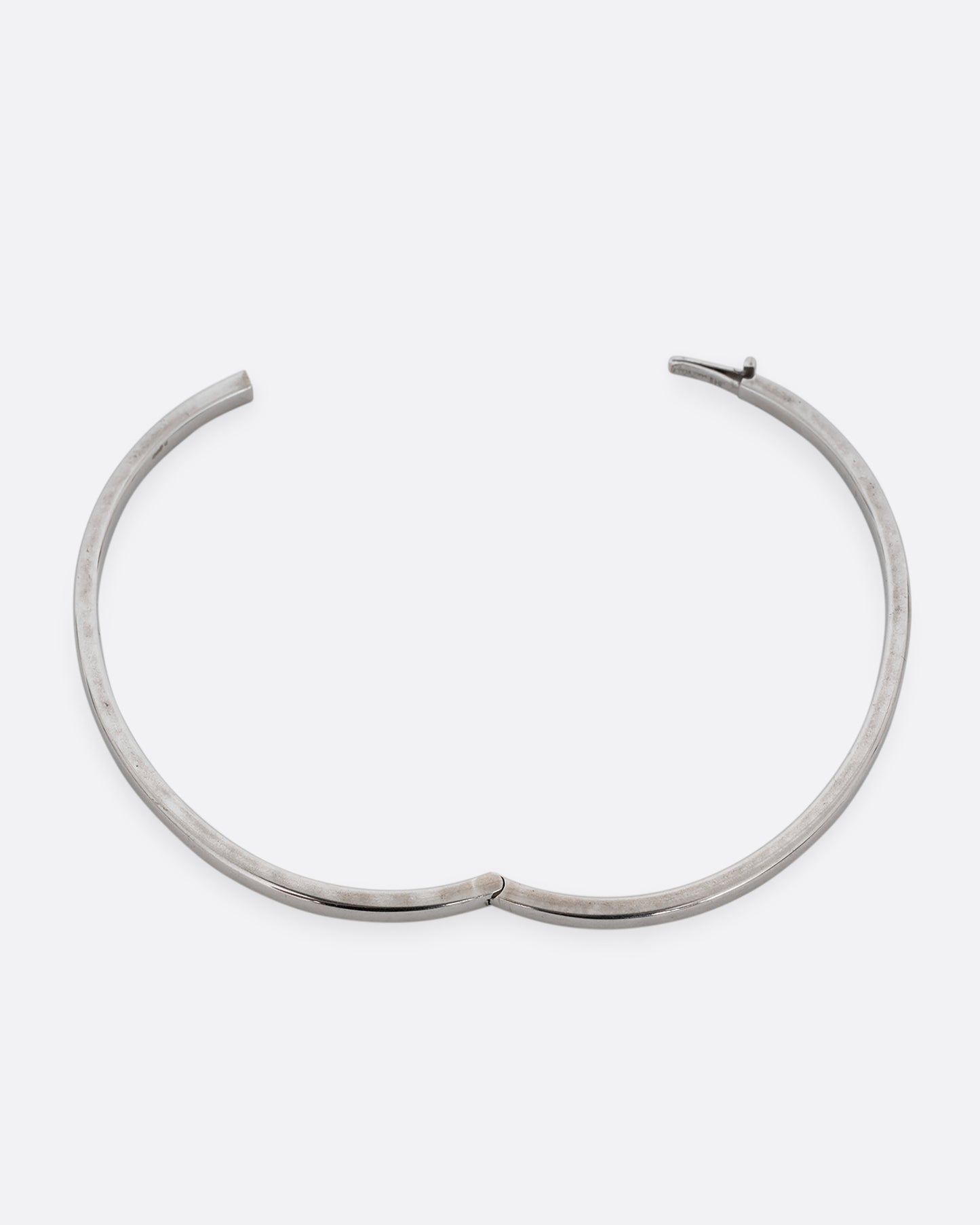 A silver hinged  bangle bracelet with squared edges. Shown open from the top.
