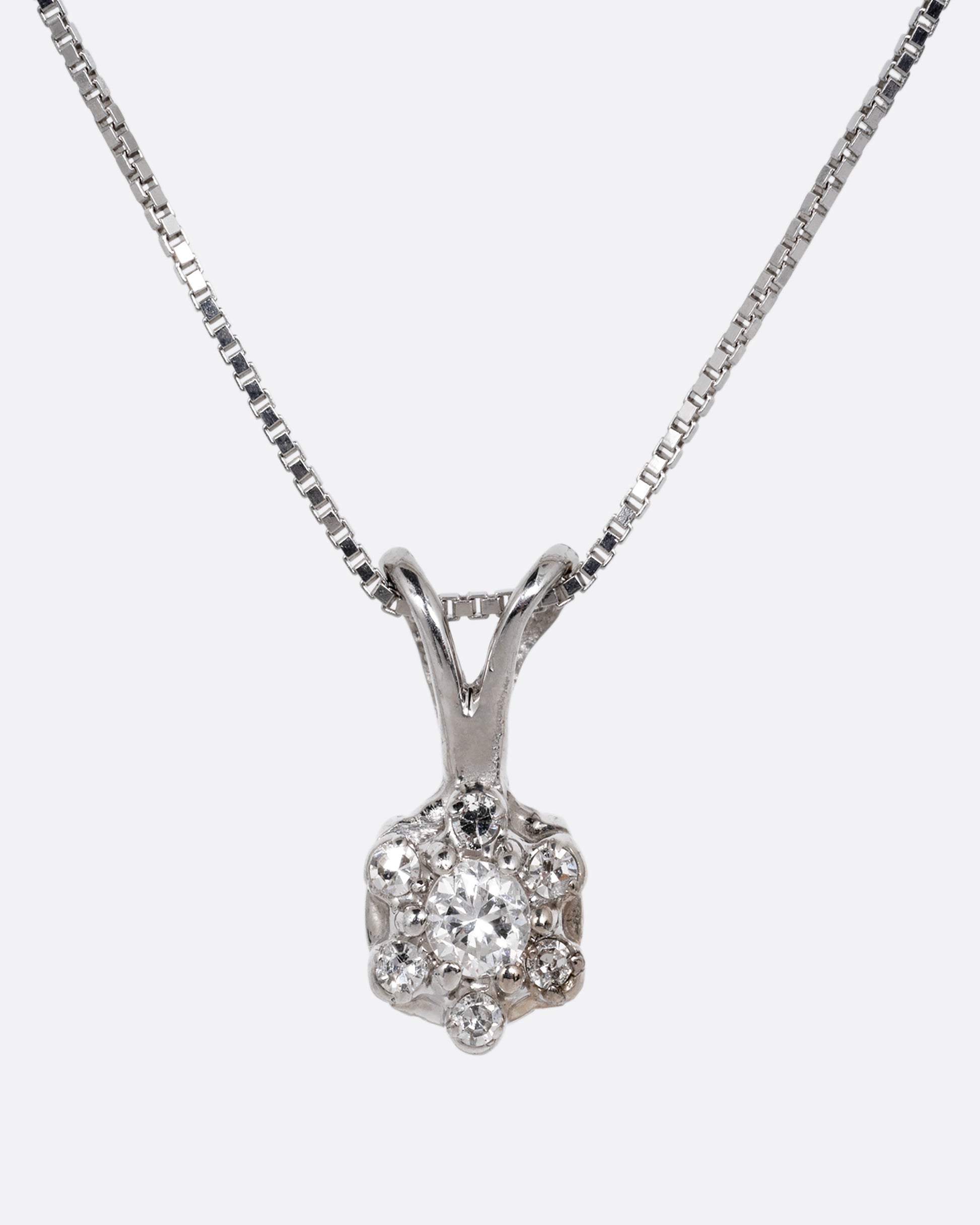 A white gold box chain necklace with a diamond studded flower shaped pendant. Shown from the front.