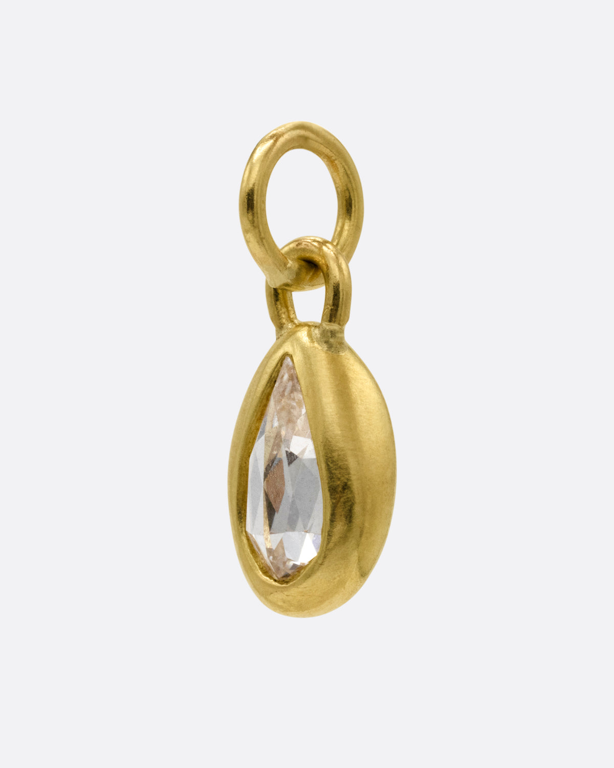 A yellow gold pear shaped and rose cut diamond charm shown from the side.