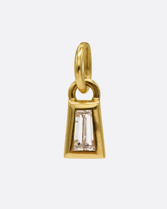 A yellow gold charm with a tapered baguette diamond, shown from the front.