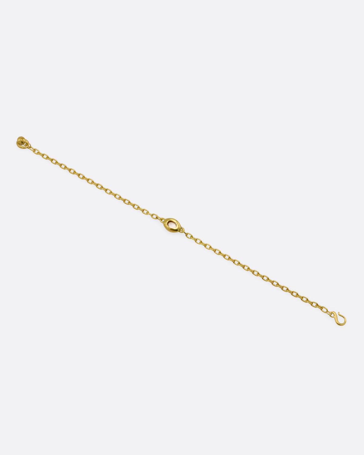 A yellow gold cable chain bracelet with an oval rose cut diamond in a chunky bezel setting, shown from the back. 