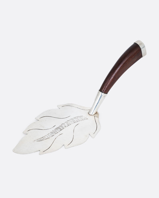 A silver leaf cake server with a wooden handle, shown from the side.