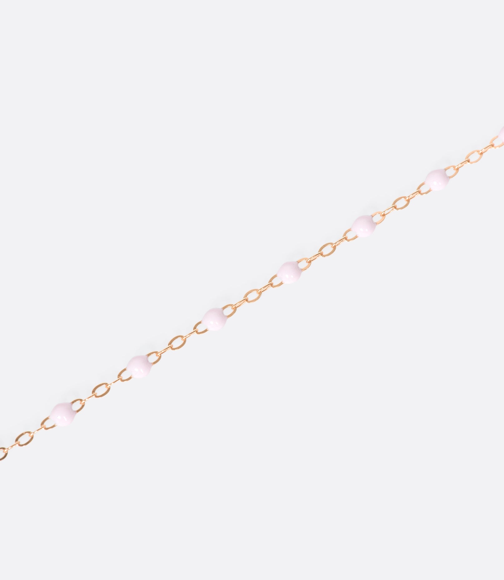 A close up view of a yellow gold cable chain necklace with red resin droplets. Shown from the side.