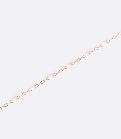 A close up view of a yellow gold cable chain necklace with red resin droplets. Shown from the side.