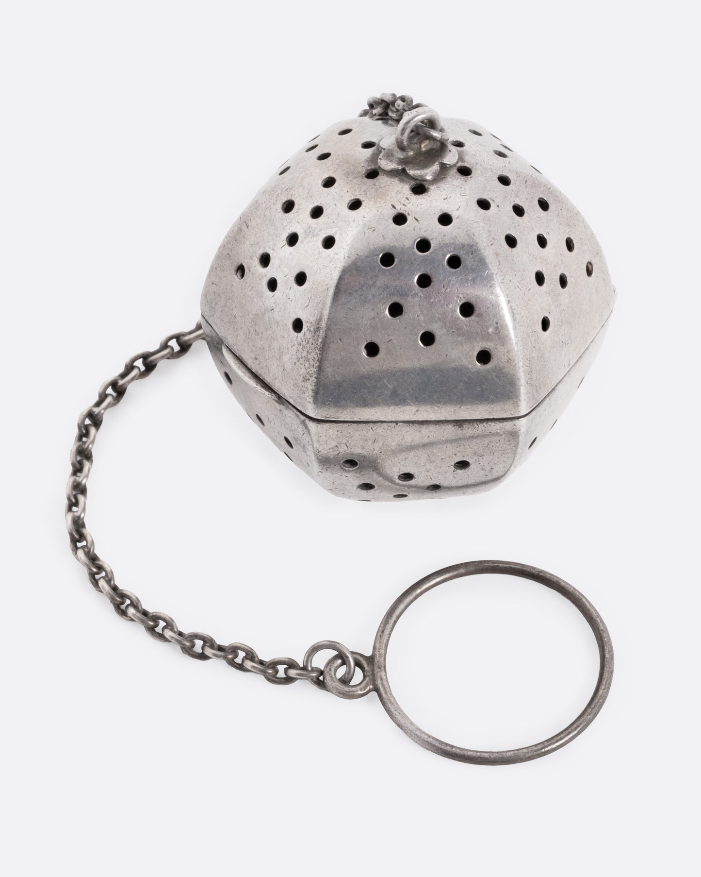 A hexagonal silver tea infuser with a chain, shown from the front.