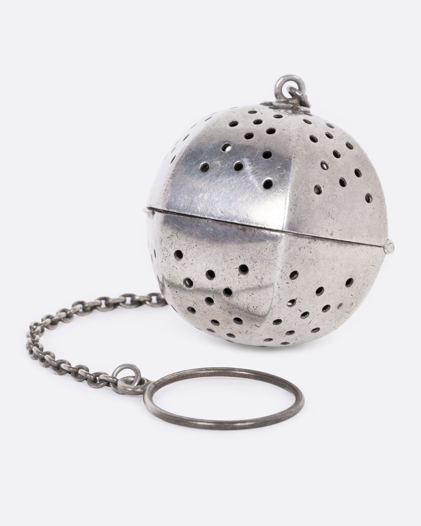 A hexagonal silver tea infuser with a chain, shown from the front.