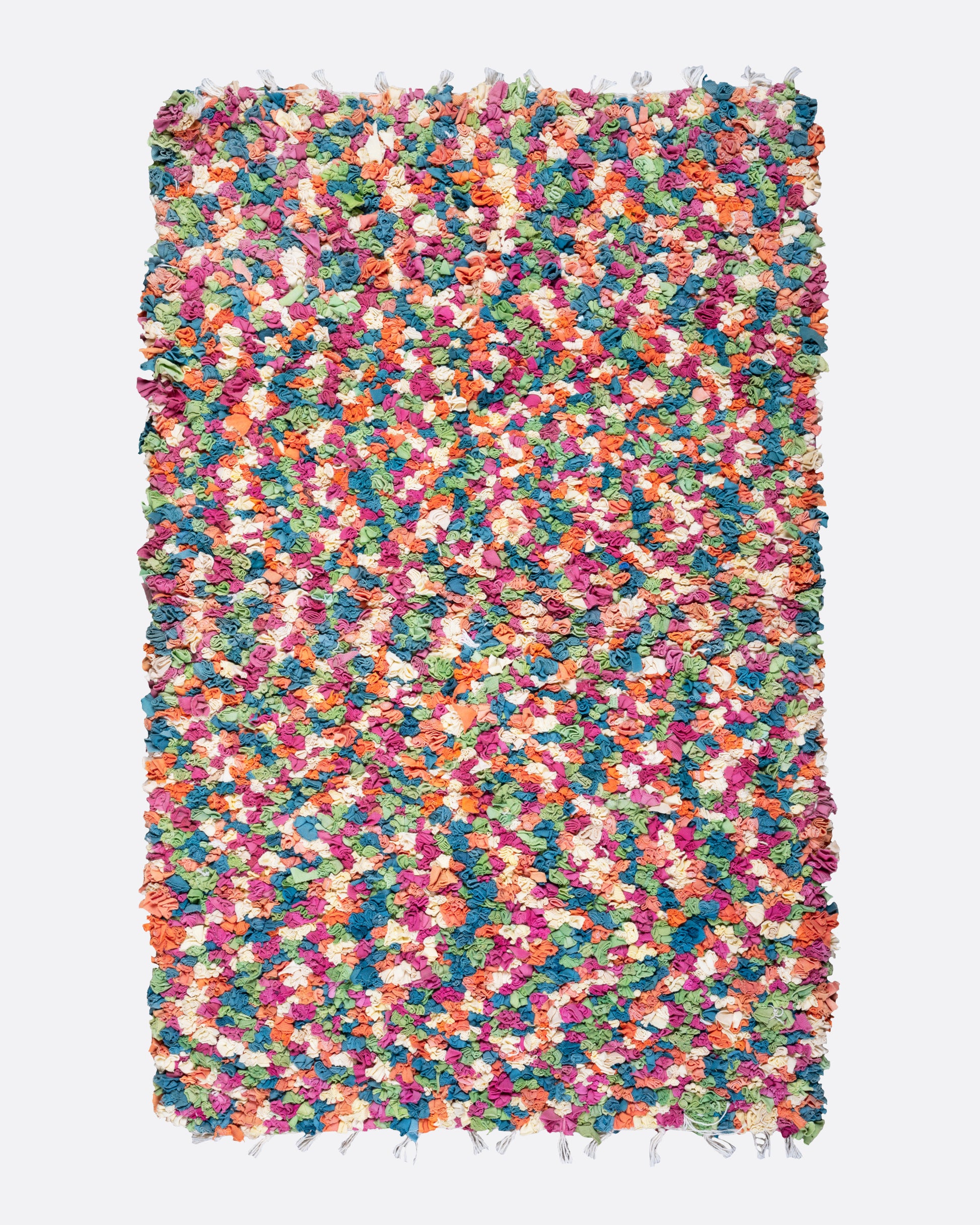 A bird's eye view of a green, red, orange, and white rectangular rag rug.
