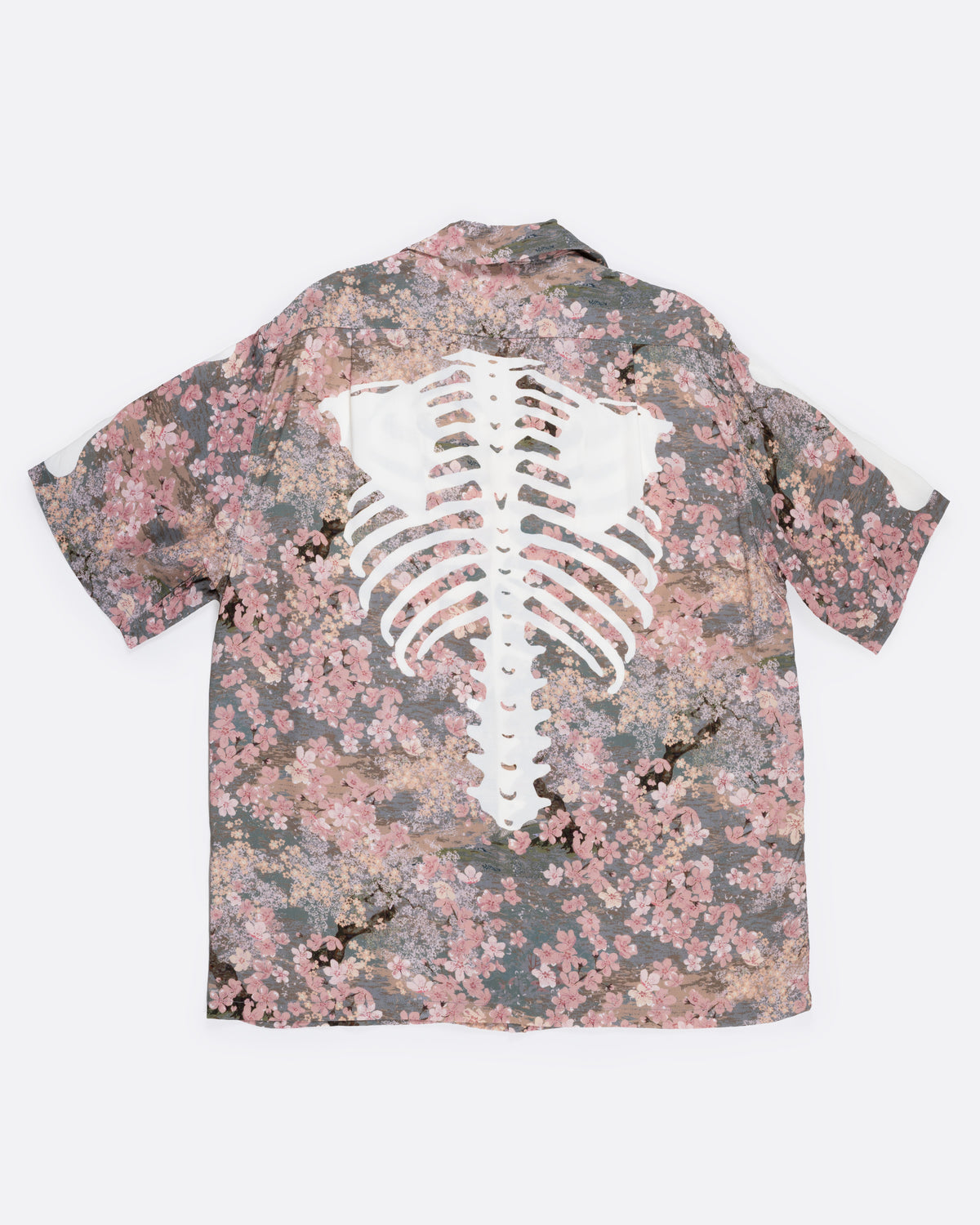 A button front short sleeve shirt with a cherry blossom print punctuated by Kapital’s skeleton motif, shown from the back.