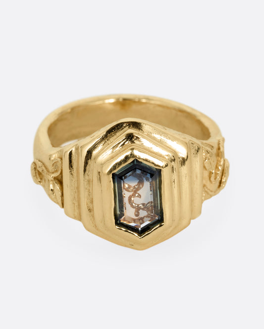 A yellow gold with a stepped center and a portrait cut bicolor tourmaline with a gold tendril that reveals itself through the stone. Shown from the front.
