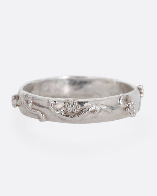 A silver ring with a grape vine motif. Shown from the front.