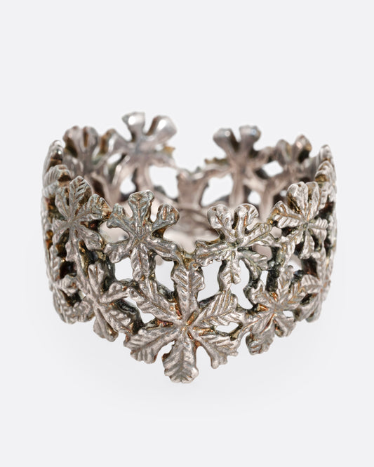 A wide silver ring with a pattern of flowers, shown from the front.