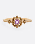 A yellow gold ring with a floral motif and pink tourmaline at the center. Shown from the front.
