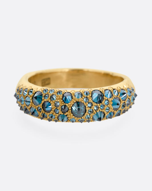 A yellow gold ring with reverse set blue diamonds, shown from the front.