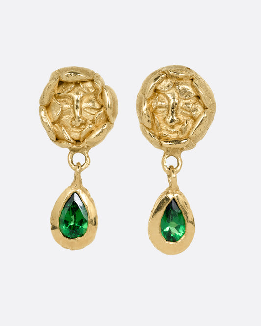 A pair of yellow gold studback earrings with faces at the center of rosebuds and a pear shaped tsavorite dangle. Shown from the front.