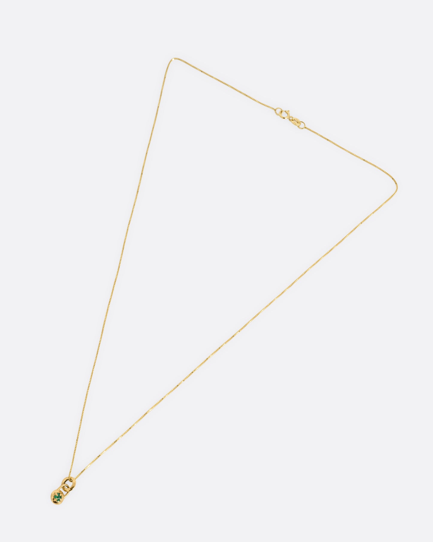 A yellow gold box chain necklace with a prong set emerald cabochon. Shown from the front.