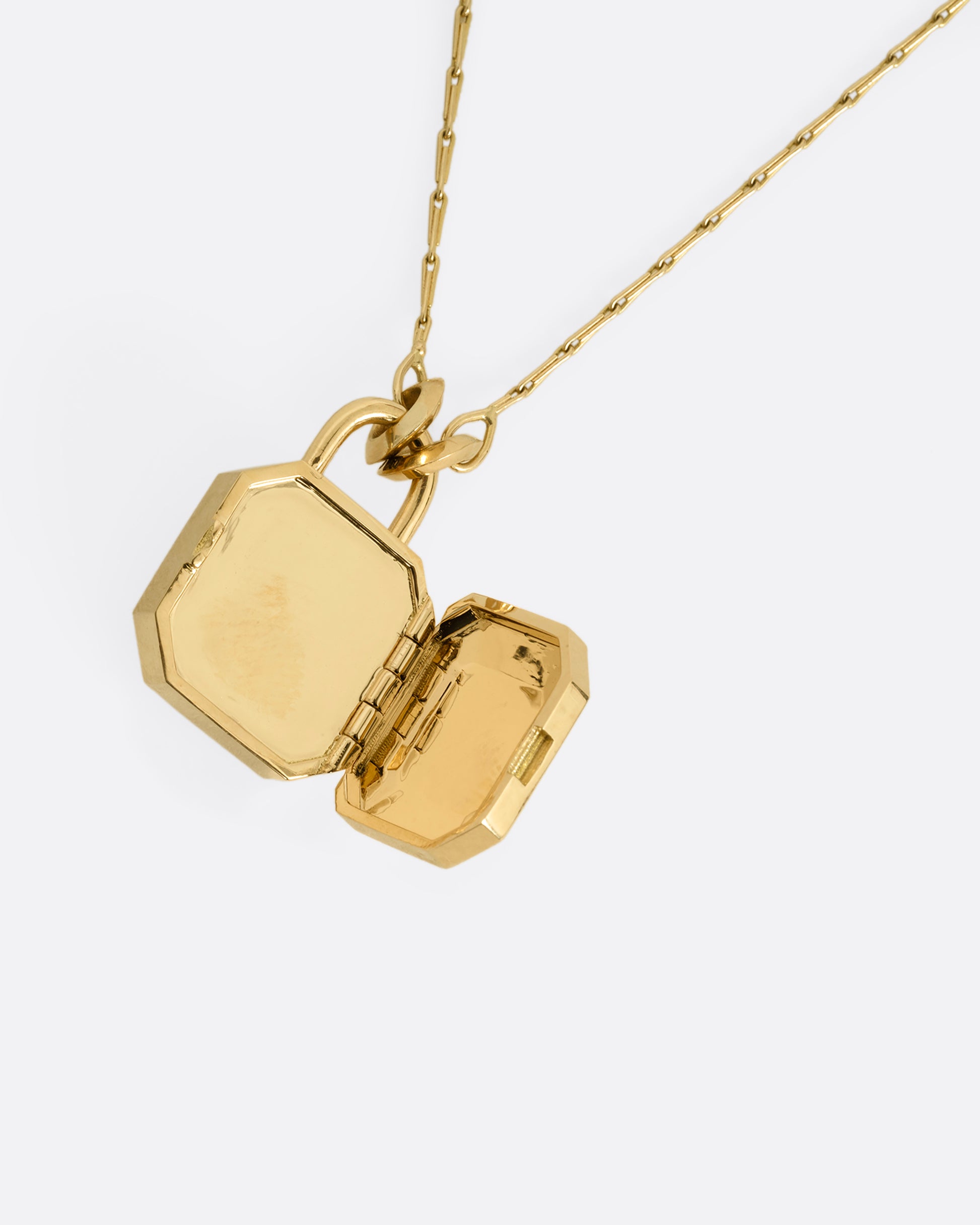 A yellow gold necklace with a padlock shaped locket pendant with multicolored sapphire on its face. Shown from the open.