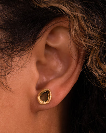 Yellow gold green sapphire stud earrings worn on an ear